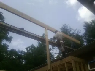 Carpenter setting a ridge beam over a new addition frame — Ice Dam Removal by Roofing Brothers in Clare