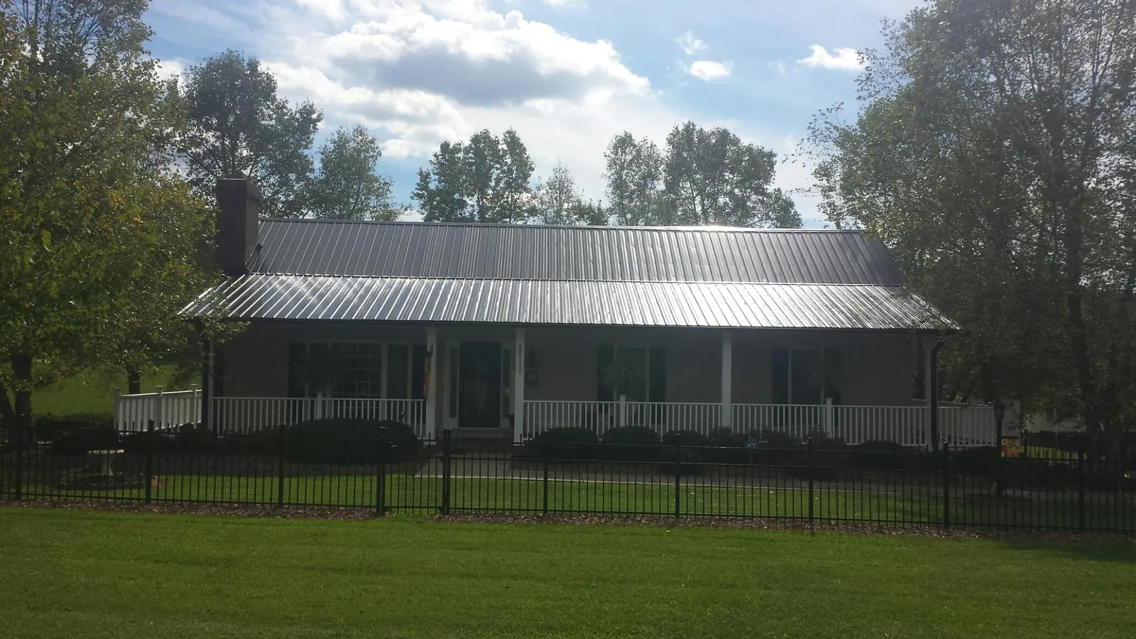 Gray metal roof on a brick ranch with a full width front porch — Gutter Guard Installation work by our crew in Clare