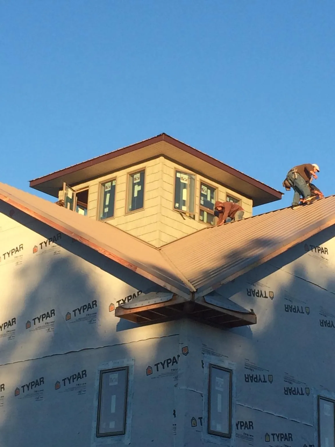 Roofers working around a rooftop cupola on a new metal roof at sunset — Roof Waterproofing in Clare by Roofing Brothers